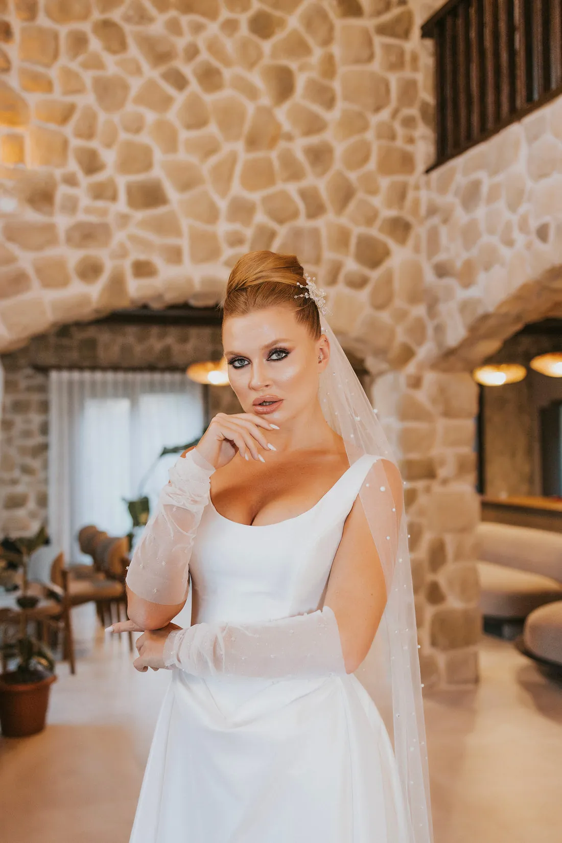 Duvak ve eldiven takmış gelin, taş salonda